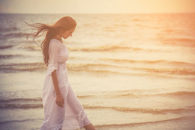 Woman wading in sea during sunset