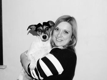 Portrait of woman holding dog at home