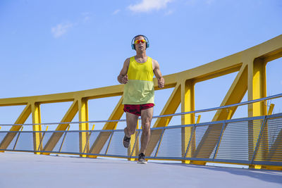 Low angle view of man standing on railing against sky