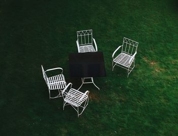 High angle view of empty chairs and table on field