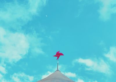 Low angle view of weather vane against blue sky