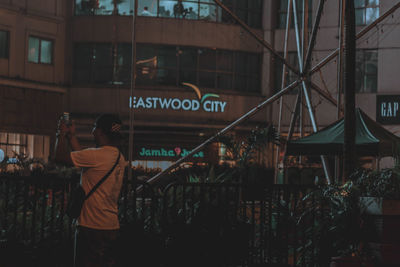 Rear view of man photographing against building