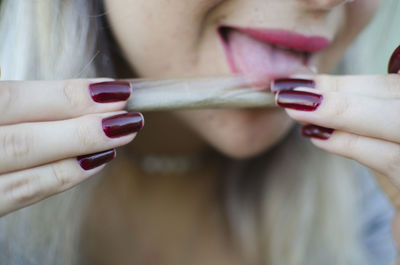 Close-up of woman licking marijuana joint