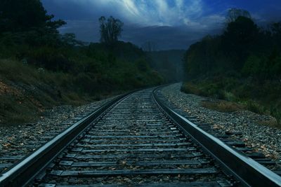 Railroad tracks by trees against sky