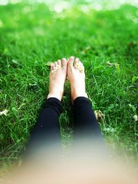 Low section of woman with flowers relaxing on grassy field