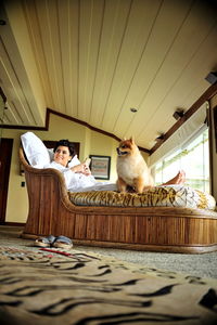 Woman relaxing with dog on bed at home