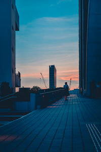 People on modern building against sky during sunset