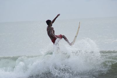 Man surfboarding on sea against sky