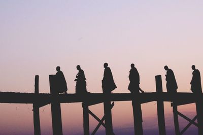 Monk walking on pier against sky