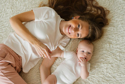 Top view of a caucasian mother lying at home on a bed with her young son.