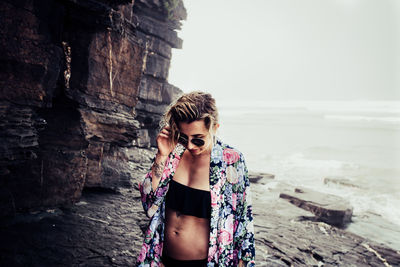 Young woman wearing sunglasses on beach against sky