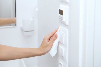 Cropped hand of woman wiping electric outlet