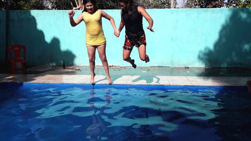 Rear view of people jumping in swimming pool
