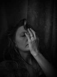 Woman with hand covering face against wall