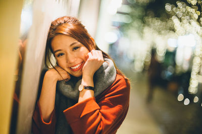 Portrait of smiling woman against illuminated lights