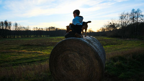 Man sitting on field against sky