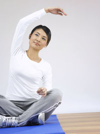 Smiling young woman doing yoga on hardwood floor