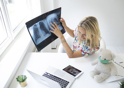 Young woman using digital tablet while sitting on table