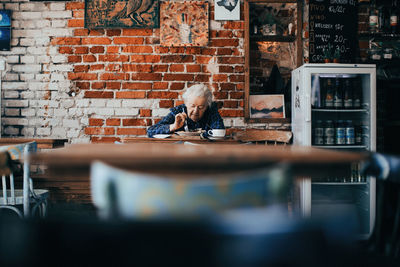 Woman using phone while sitting on table