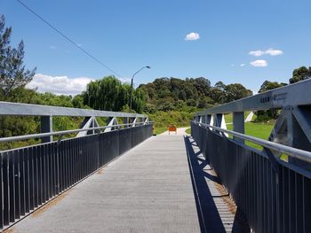 Footbridge amidst trees against sky