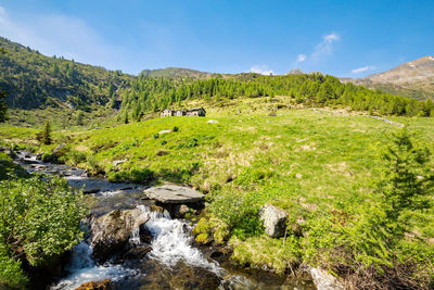 Scenic view of stream flowing through rocks against sky