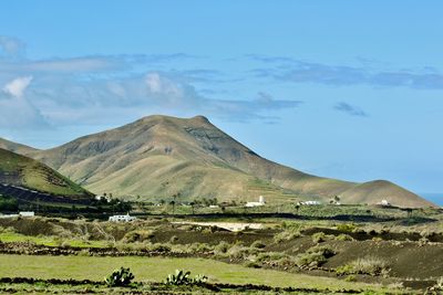 Scenic view of field and mountains against blue sky