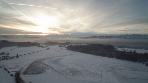 Snow covered road against sky during sunset