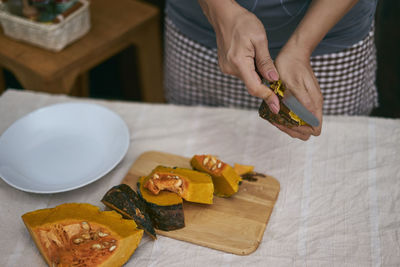 Midsection of woman cutting pumpkin at table