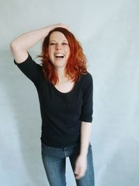 Portrait of happy mid adult woman with redhead standing against wall at home