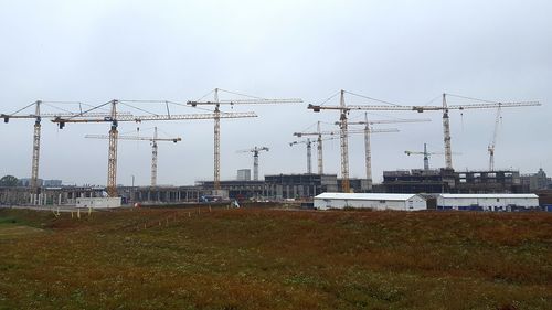 Cranes at construction site in city against sky