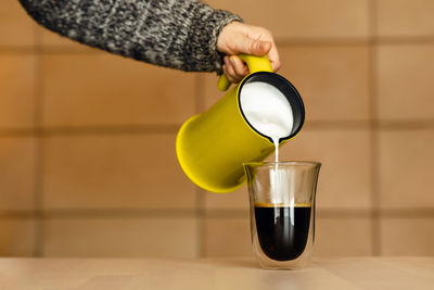 Woman in gray sweater makes homemade cappuccino.