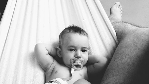 Low section of father with cute baby son relaxing on hammock