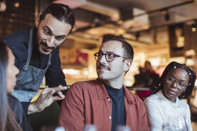 Waiter talking with friends in restaurant during dinner