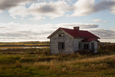 An old abandoned house by a small swamp lake. the windows of the house have been broken.