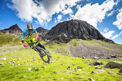 Man riding bicycle on mountain against sky