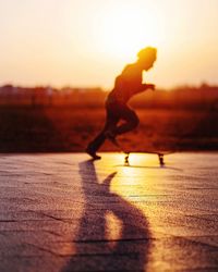 Side view of silhouette man running on street against sky during sunset