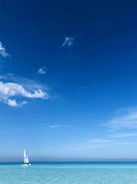 Sailboat in sea against blue sky