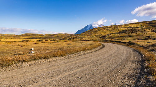 Gravel road through the wild grasslands of patagonia, torres del paine national park, chile