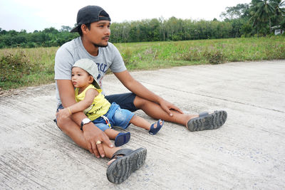 Full length of a boy sitting on stone wall