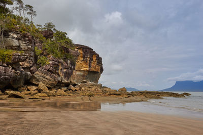 Rock formation on beach against sky