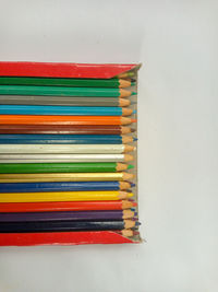 Close-up of multi colored pencils on table against white background