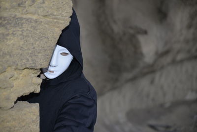 Midsection of person wearing mask standing on rock