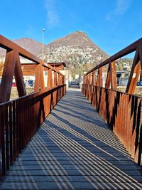 Footbridge leading towards mountain against sky