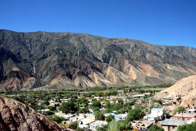 Aerial view of townscape and mountains against clear blue sky