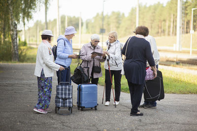 A group of positive senior elderly people travelers waiting for train before going on a trip