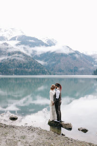 A loving married couple the bride and groom in suits celebrate wedding near the mountains and water