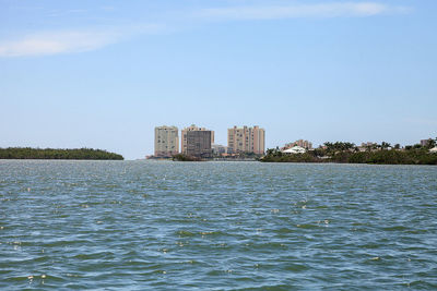 Buildings by sea against sky