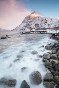 Scenic view of sea by mountain against sky