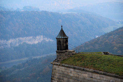 Castle by building against mountain range
