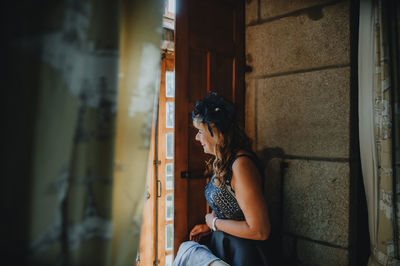 Young woman looking away while sitting on floor